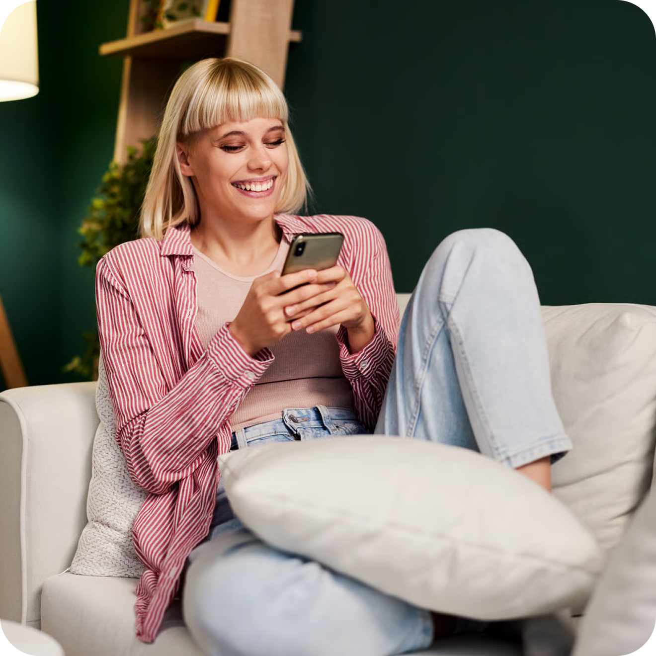 Femme souriante consultant son smartphone sur un canapé — UX claire qui convertit